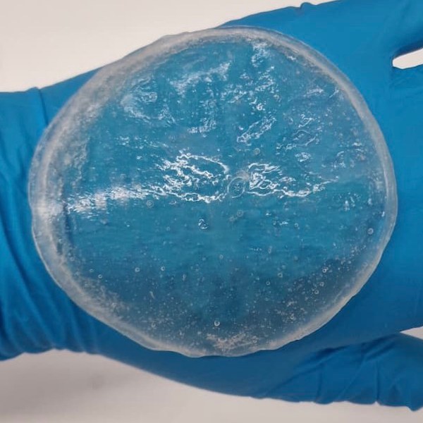 AMINA as a clear gel, held in a gloved hand.